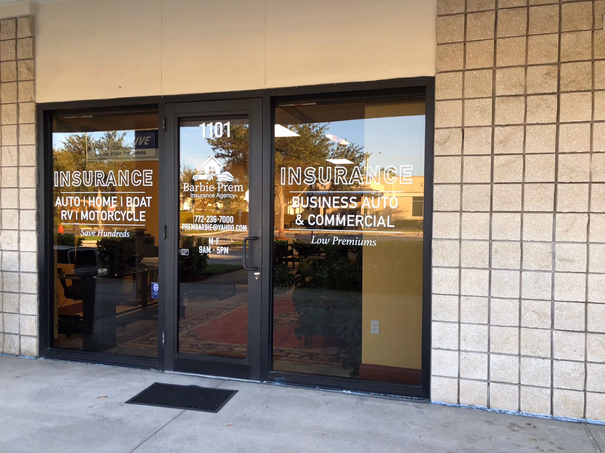 Front glass doors of Barbie Prem Insurance Agency with text listing auto, home, boat, RV, motorcycle, business auto, and commercial insurance.