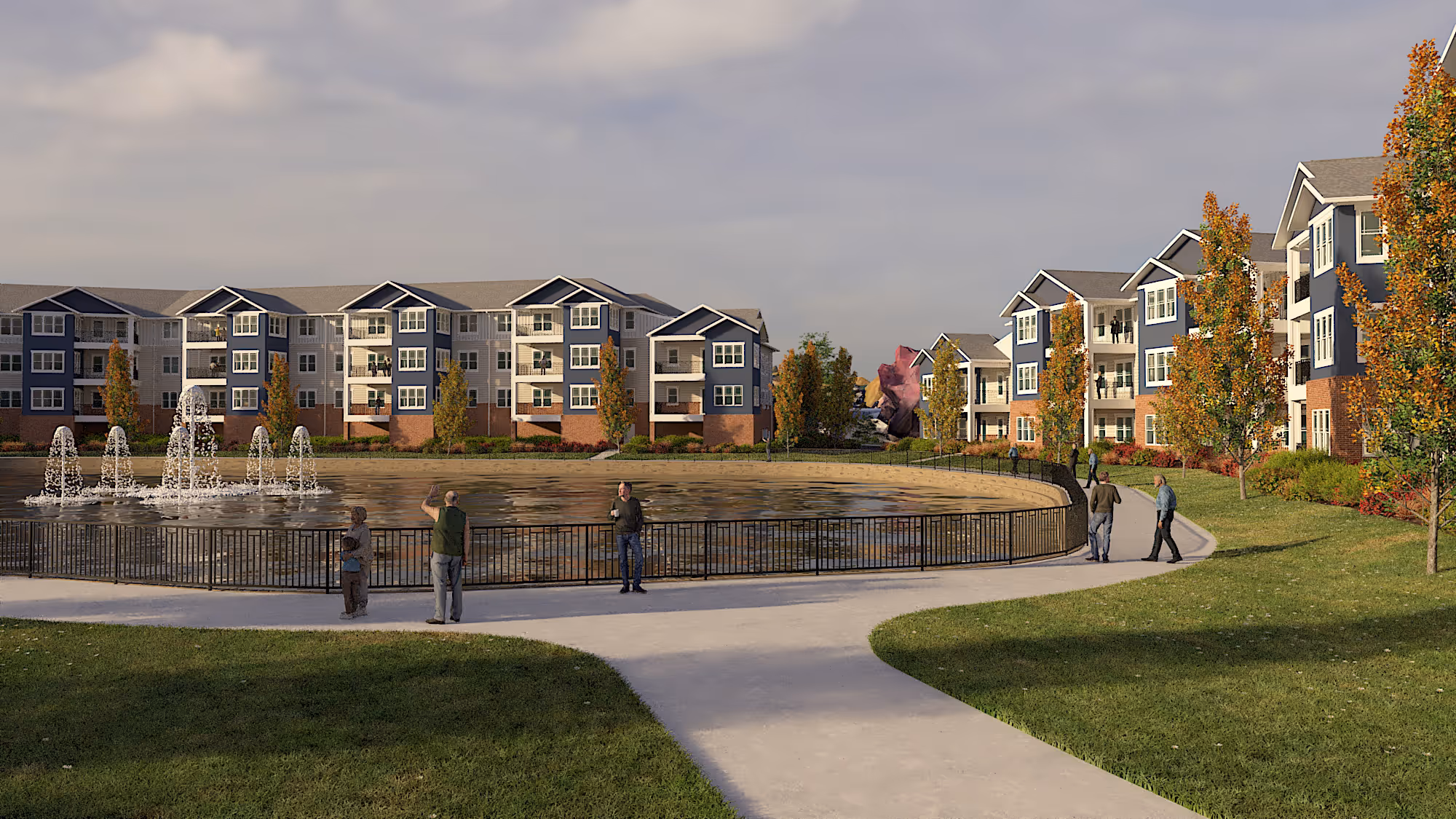 Residential apartment complex with blue and white buildings surrounding a large pond with fountains, trees with autumn foliage, and people walking on sidewalks.
