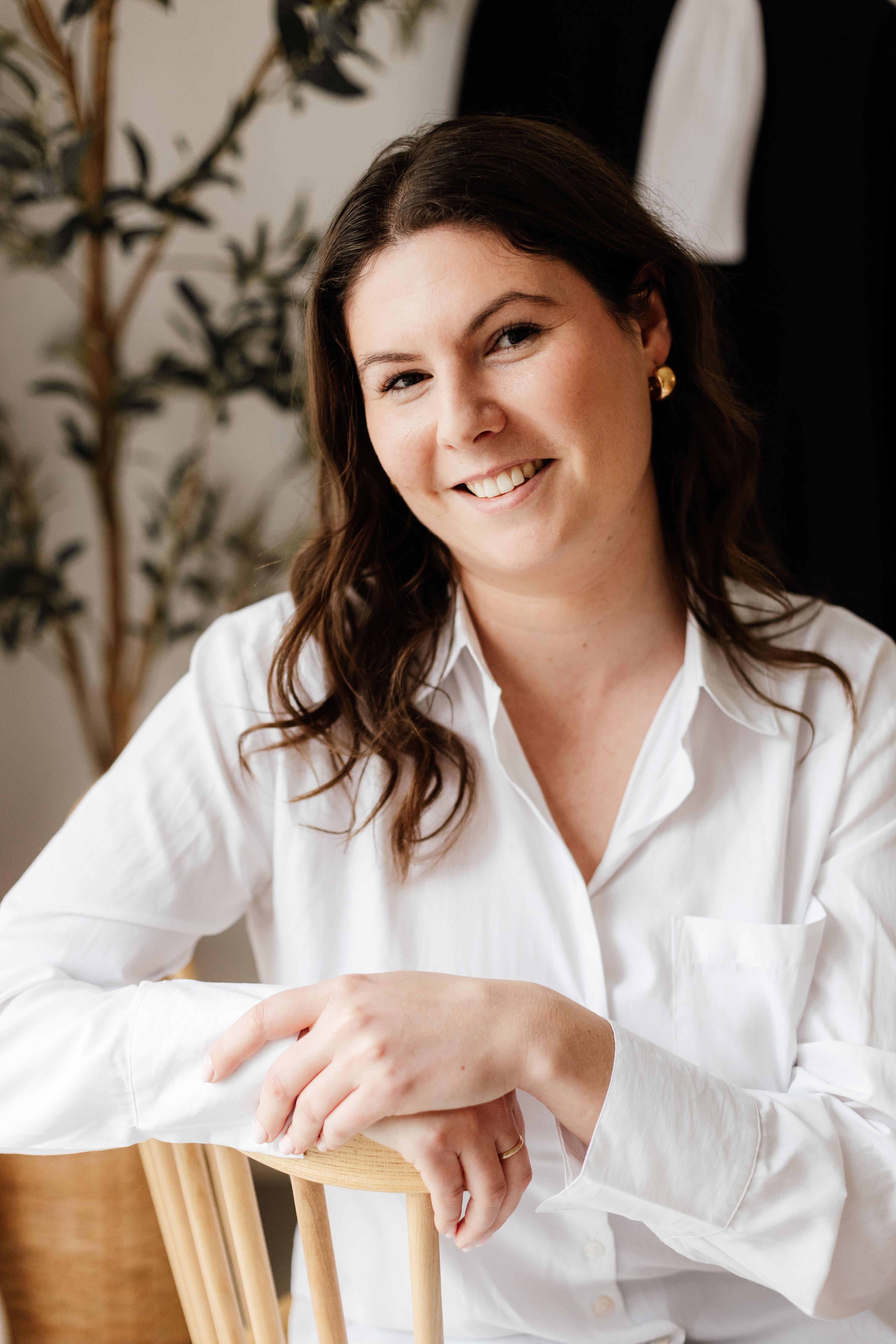 Portrait en noir et blanc d'une femme souriante avec des cheveux ondulés portant une chemise blanche.