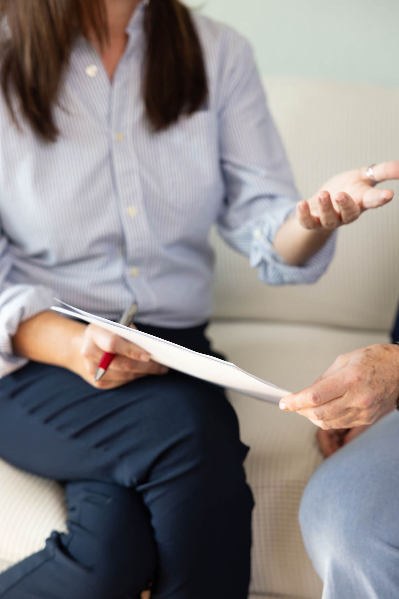 Female professional reviewing paperwork with an older adult during a one-on-one support conversation indoors