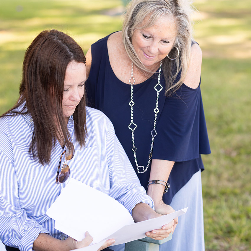 Two women reviewing paperwork together outdoors, discussing important decisions and next steps with supportive guidance