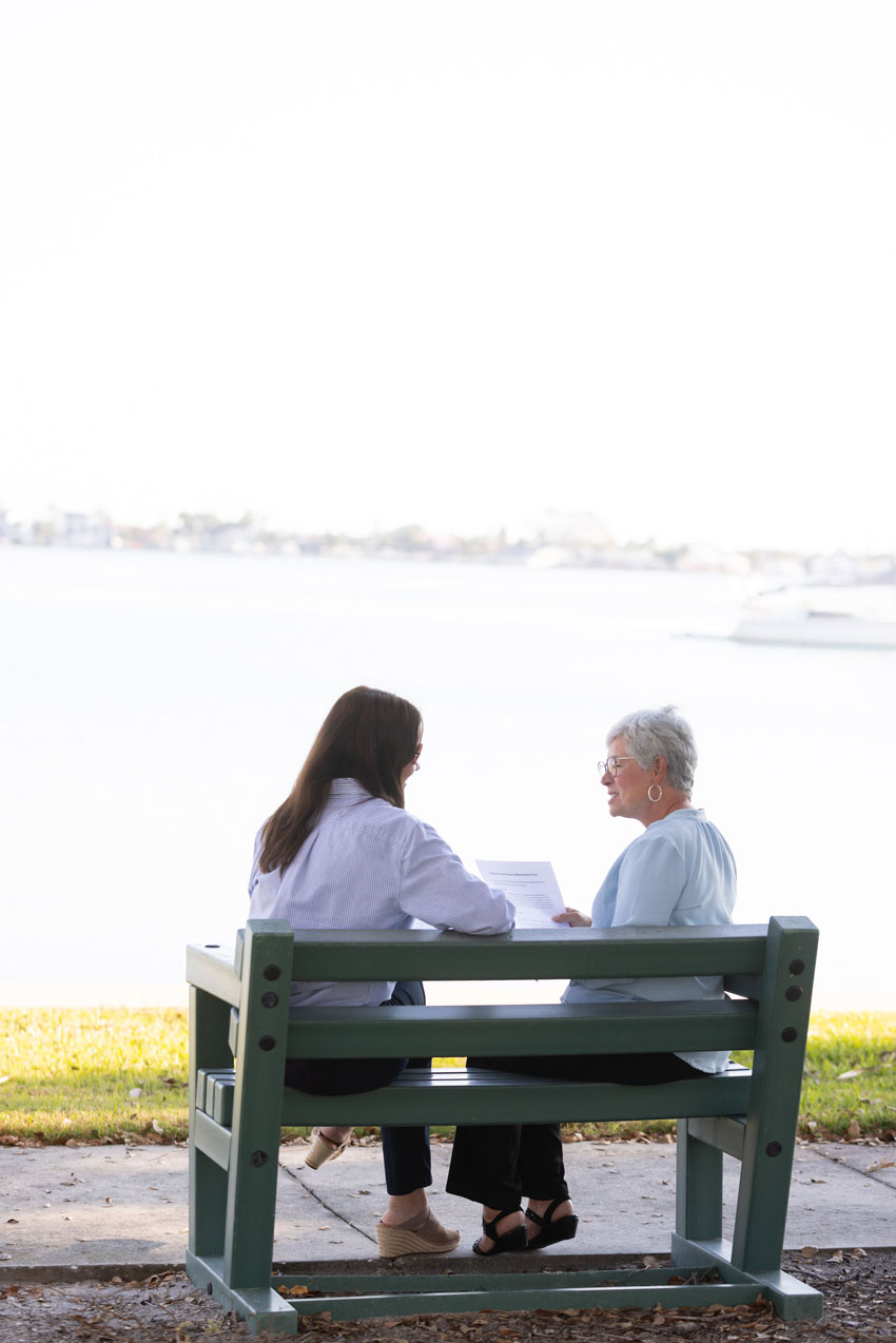 Geriatric care manager sitting with an older adult on a park bench