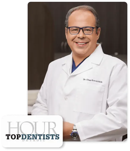Smiling male dentist with glasses wearing a white coat labeled Dr. Oleg Krivichkin.