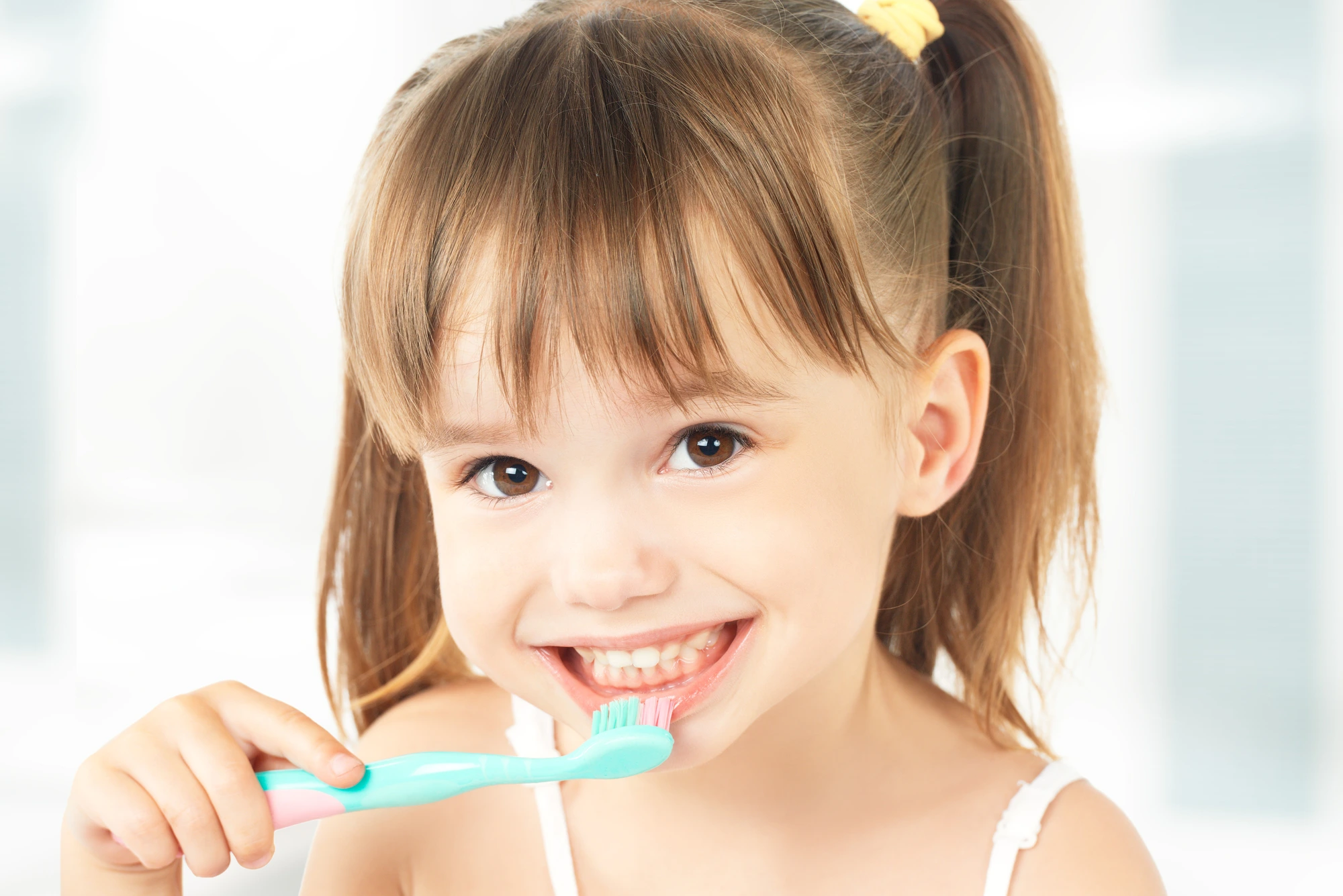 little girl brushing her teeth after learning how to at the family dentist in Southfield, MI