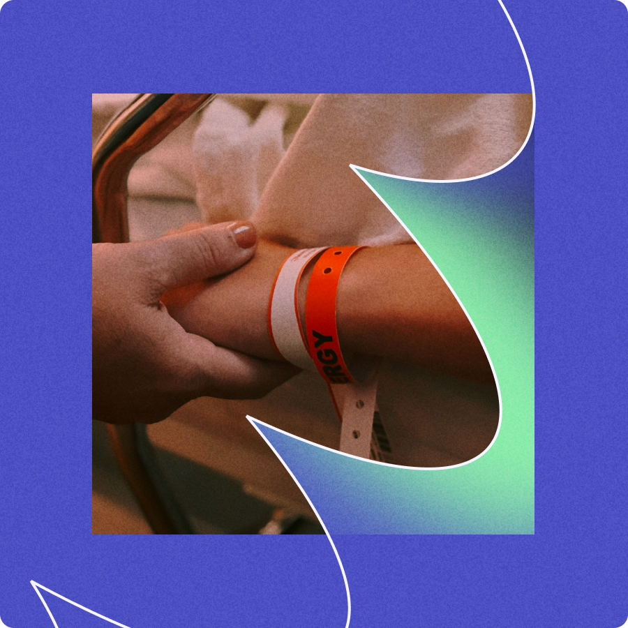 Two hands gently holding a wrist with hospital wristbands, including an orange one labeled 'ALLERGY'.