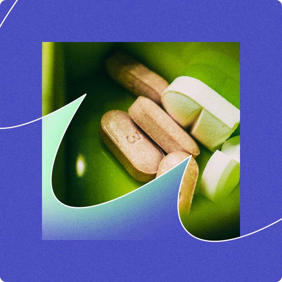 Close-up of several brown and white tablets inside a green container with a blue abstract border.