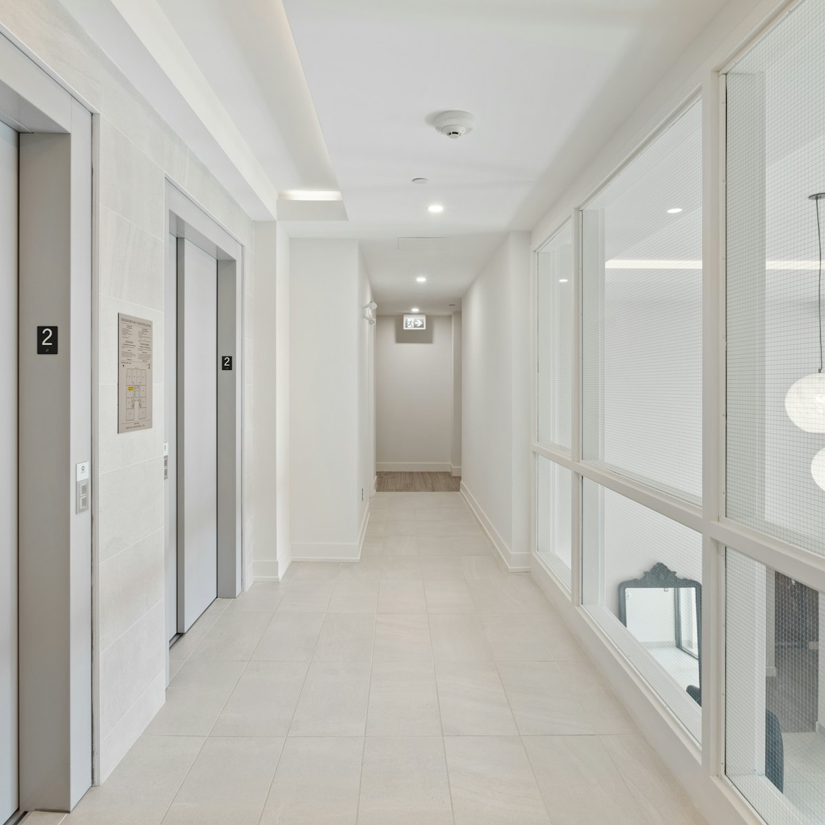 Clean, bright hallway in a multi-unit residential building with elevator doors and tiled floors