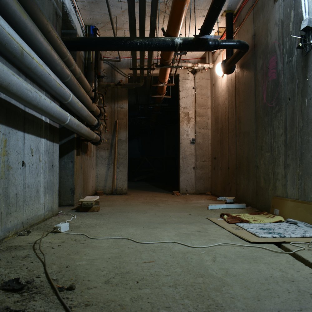 Basement service corridor with overhead pipes and a concrete floor