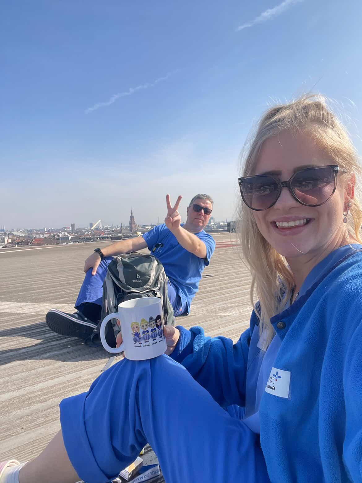 Zwei Pflegekräfte in blauer Arbeitskleidung bei einer Pause im Freien