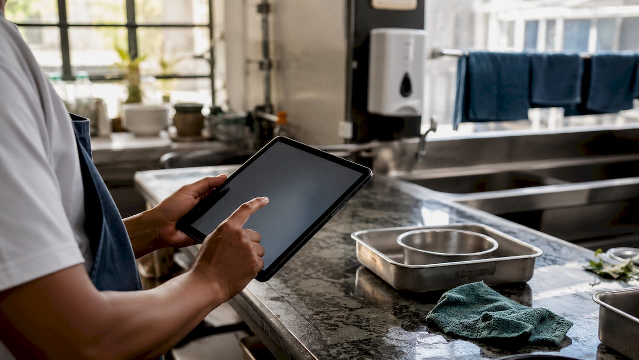Hands using digital hygiene audit tool in kitchen
