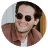 Circular portrait of a person wearing sunglasses and smiling.