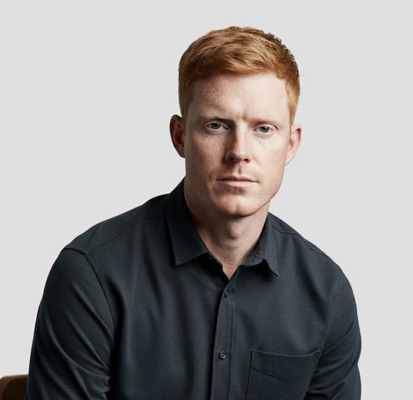 Portrait of a man sitting on a chair, looking forward.