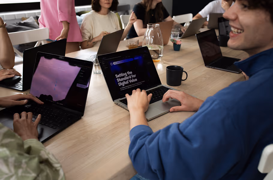 Group of people working on laptops around a conference table during a meeting.