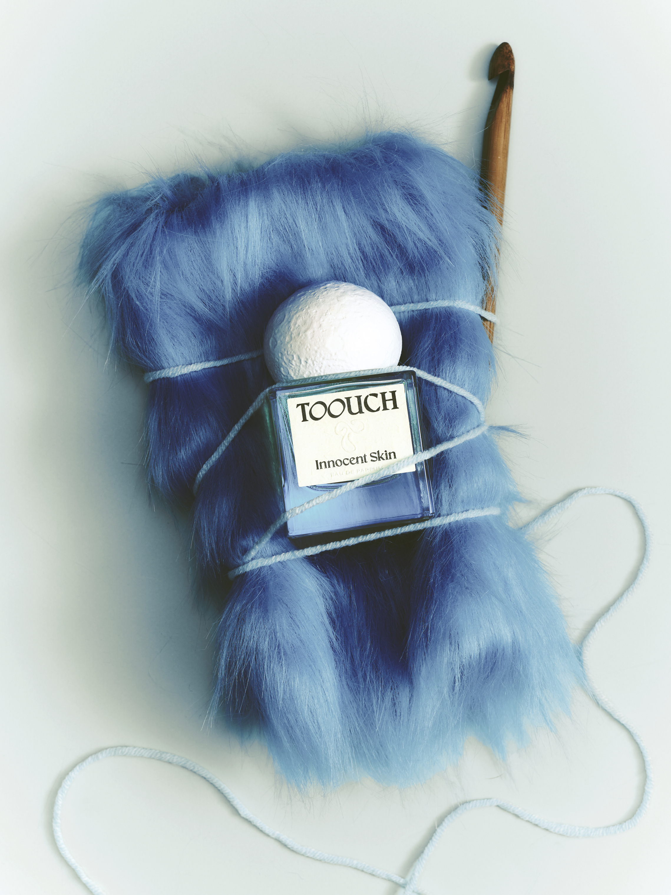 Toouch Scent perfume bottle styled on blue faux fur
