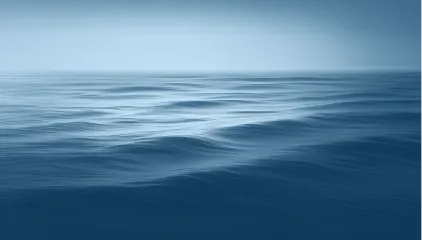 Sanft wellende Wasseroberfläche unter einem klaren Himmel.