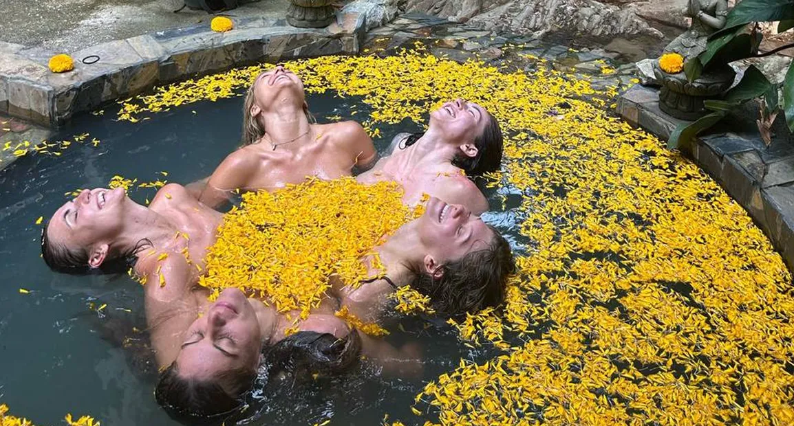 Guests relaxing in natural pool with yellow flower petals