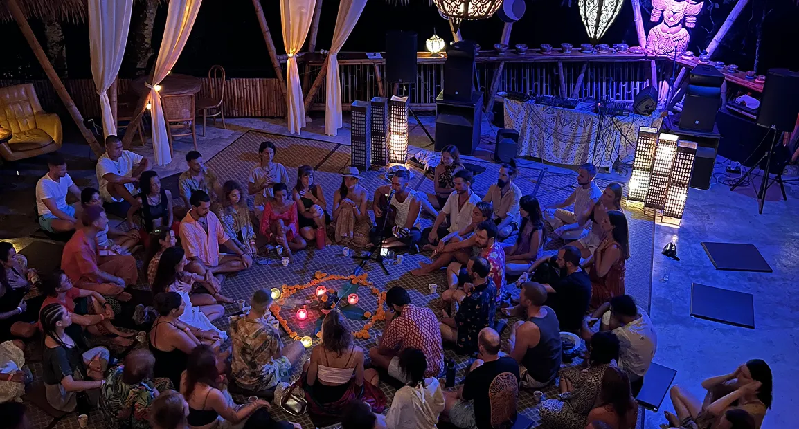 Evening gathering with guests sitting in circle around candle heart arrangement at Shivari retreat