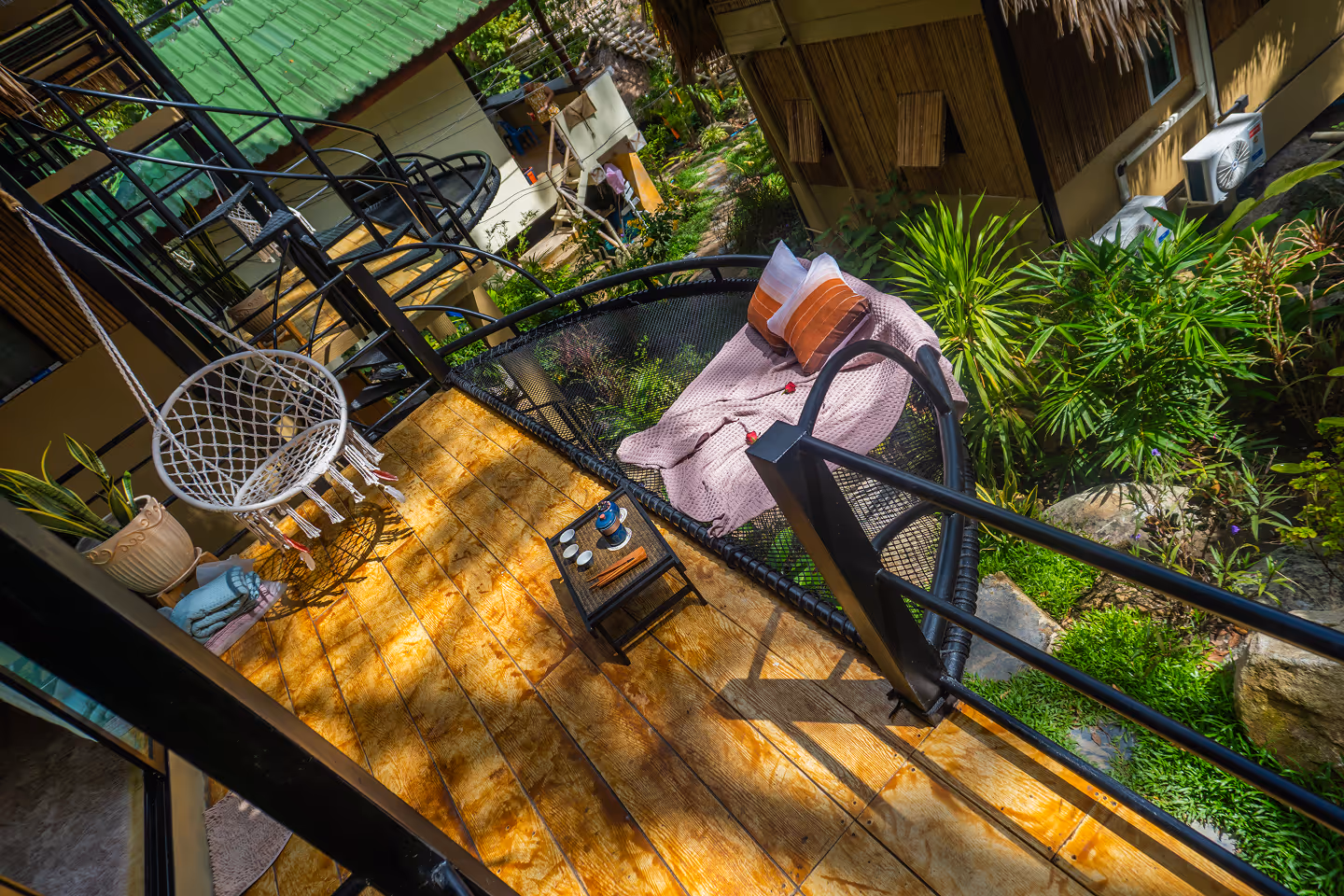 Wooden balcony with hanging chair overlooking tropical jungle