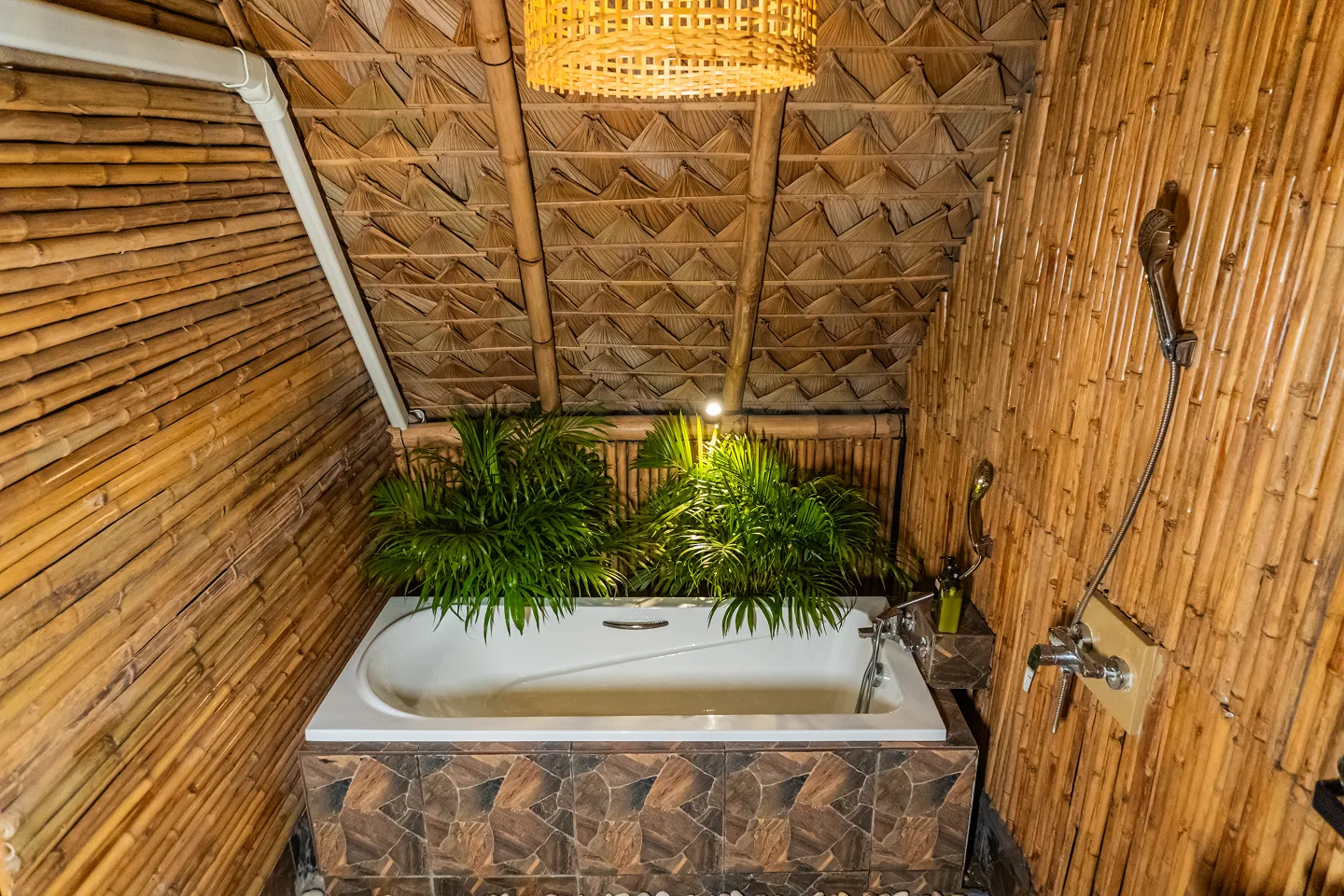Bathroom with bathtub surrounded by tropical plants and bamboo walls