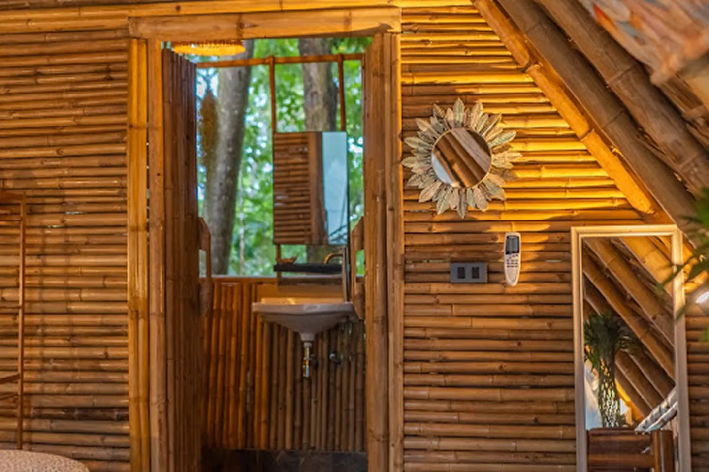 Bathroom vanity with sun-shaped mirror and bamboo walls in Mansard room