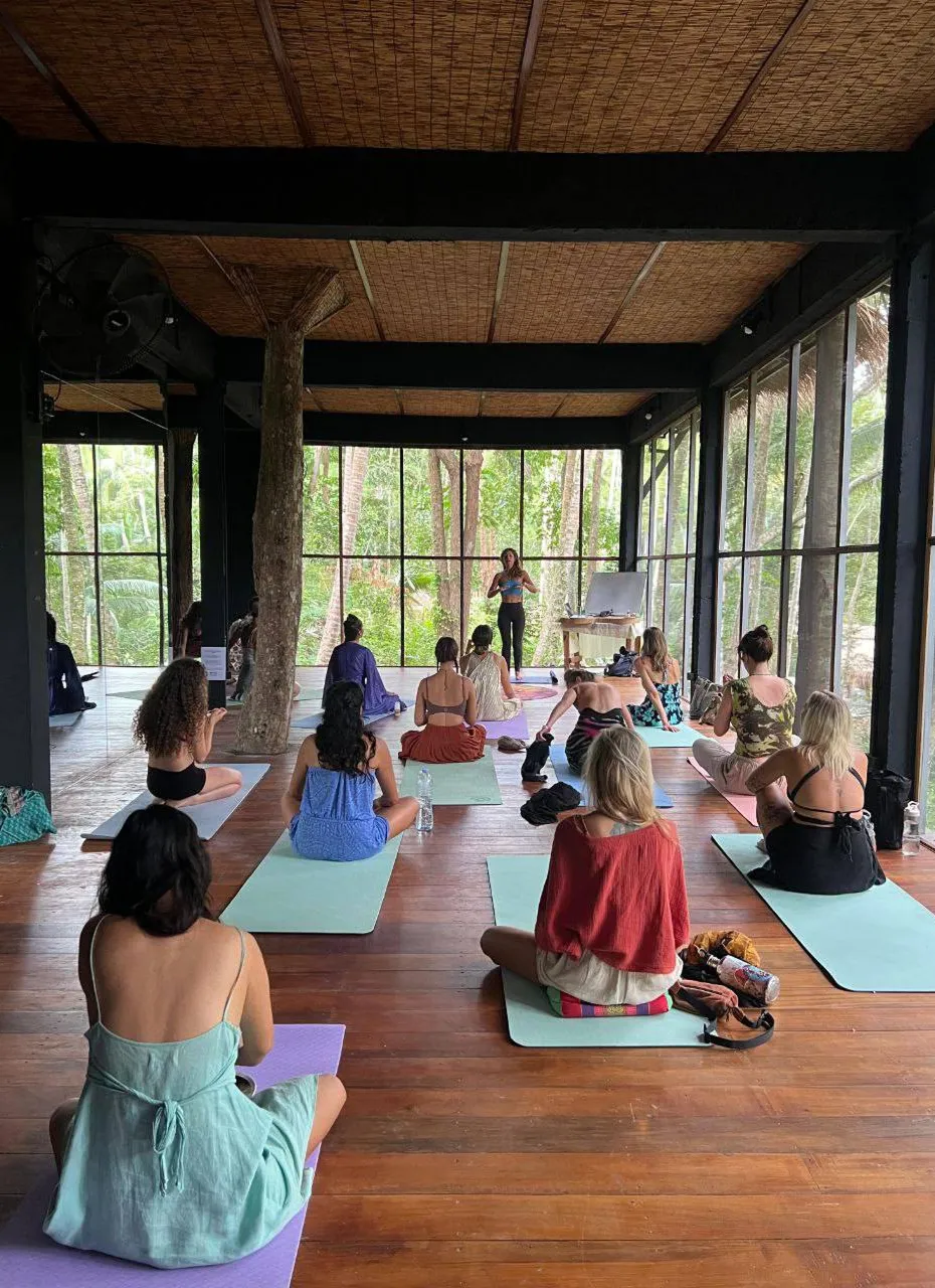 Group yoga session in open-air shala with jungle and river views