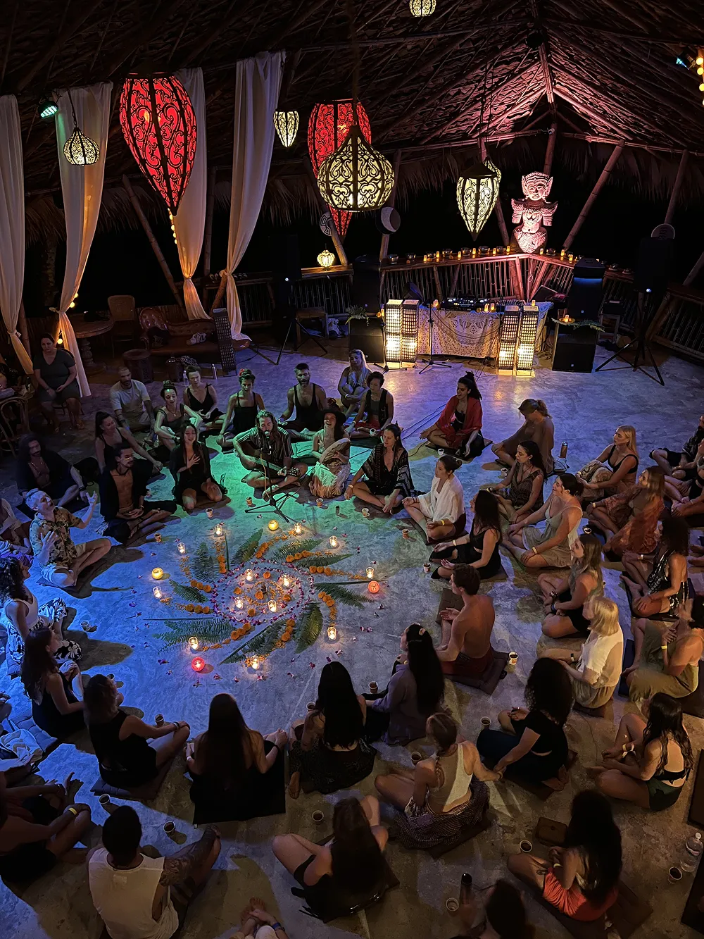 Evening candle ceremony with guests sitting in circle in illuminated pavilion