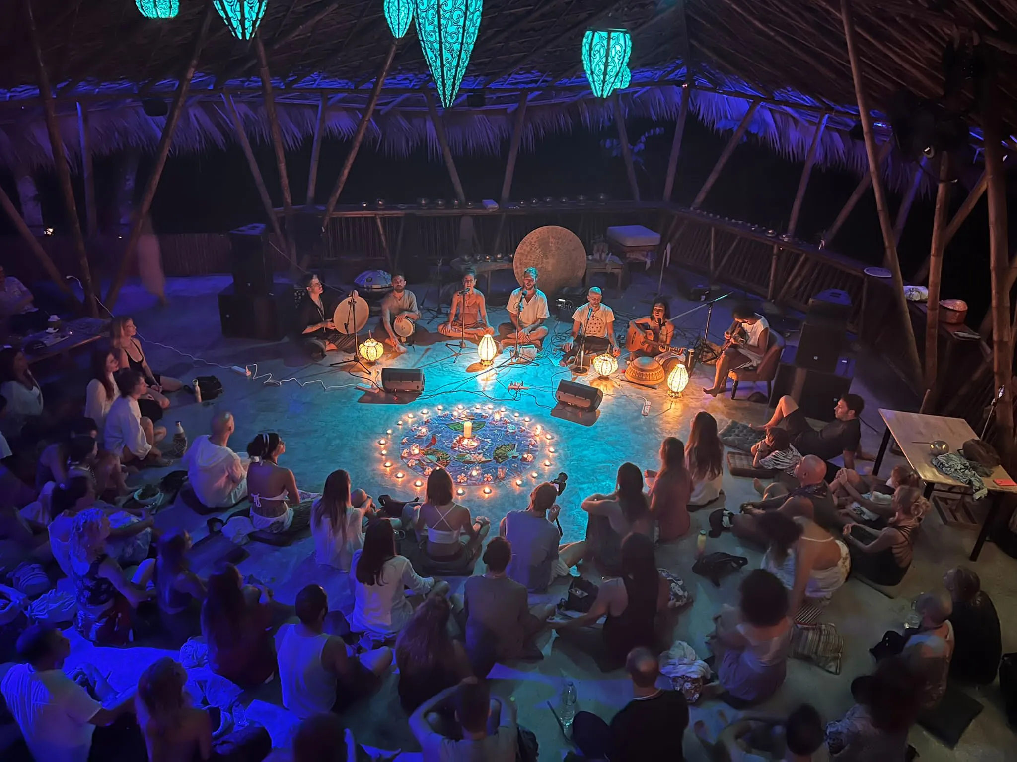 Community circle ceremony with candles in blue-lit shala