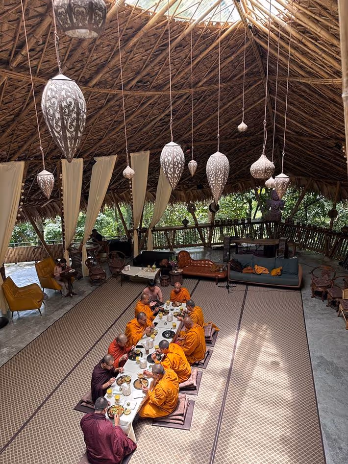 Wooden deck with hanging chair and cushions surrounded by tropical plants