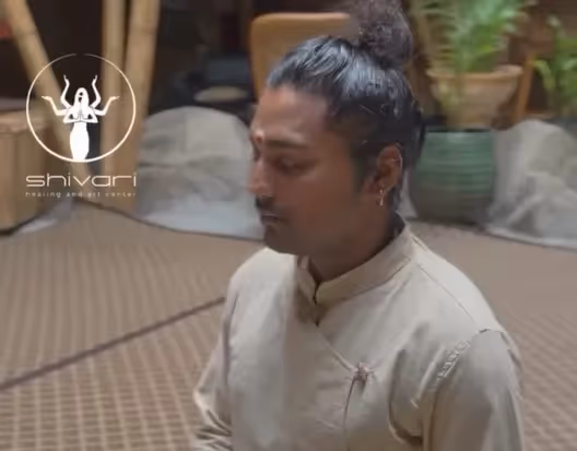 Man meditating in wellness retreat space with Shivari logo