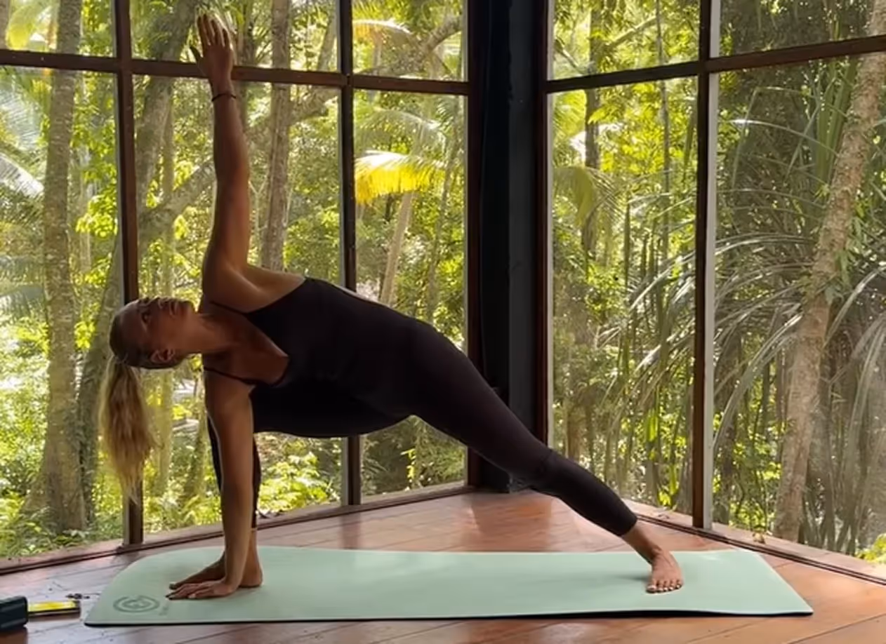 Woman practicing yoga pose in open-air studio overlooking tropical jungle