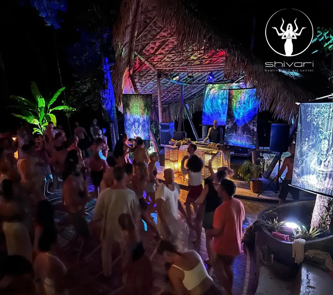 Evening dance event at tropical venue with DJ and colorful projections