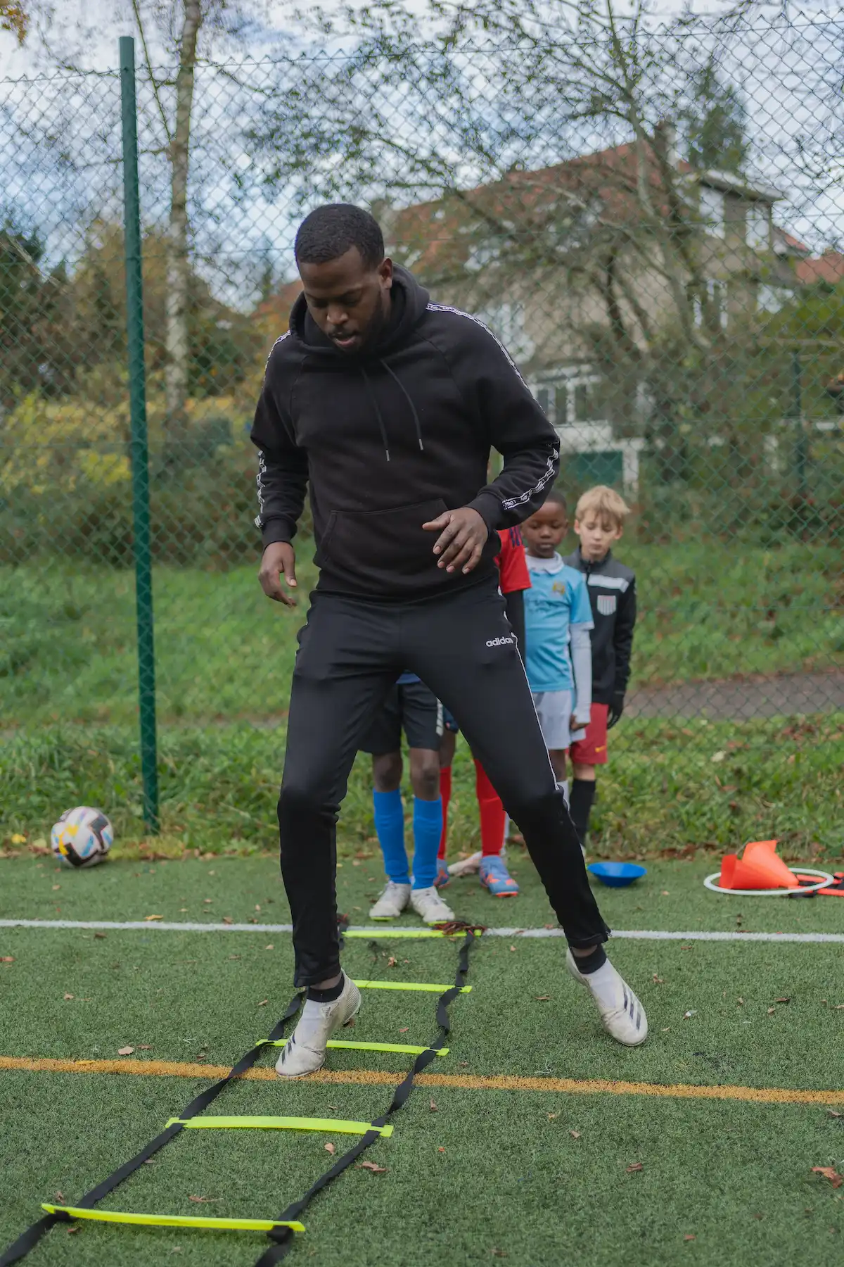 photo coach Patrick qui montre aux enfants un exercice de coordination aux enfants sur un terrain de football