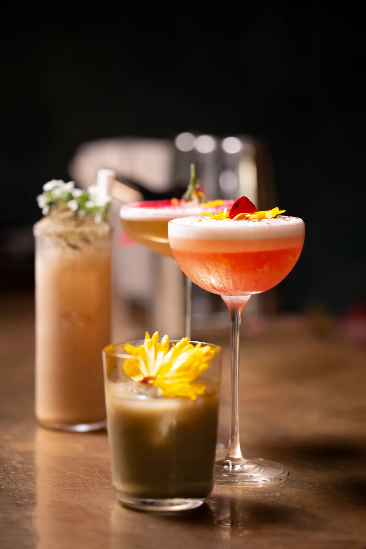 Trois cocktails de signature alignés sur un comptoir en bois