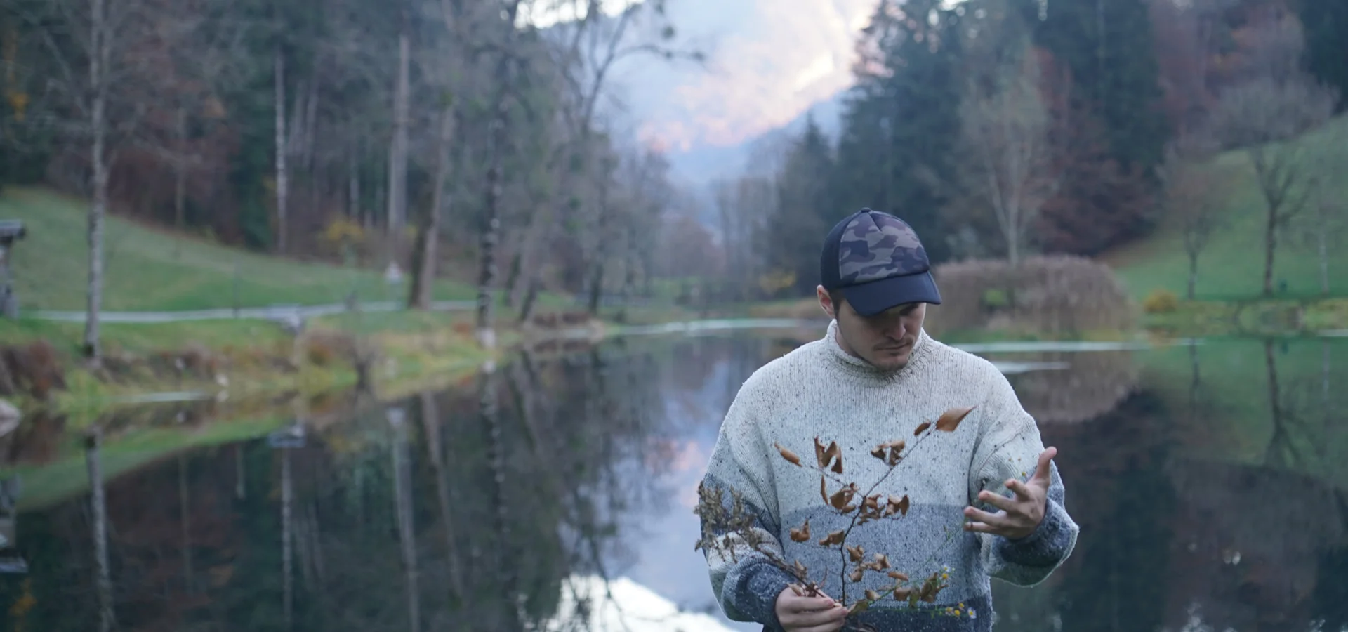 Victor Weber cueillant des plantes sauvages au bord d'un lac de montagne