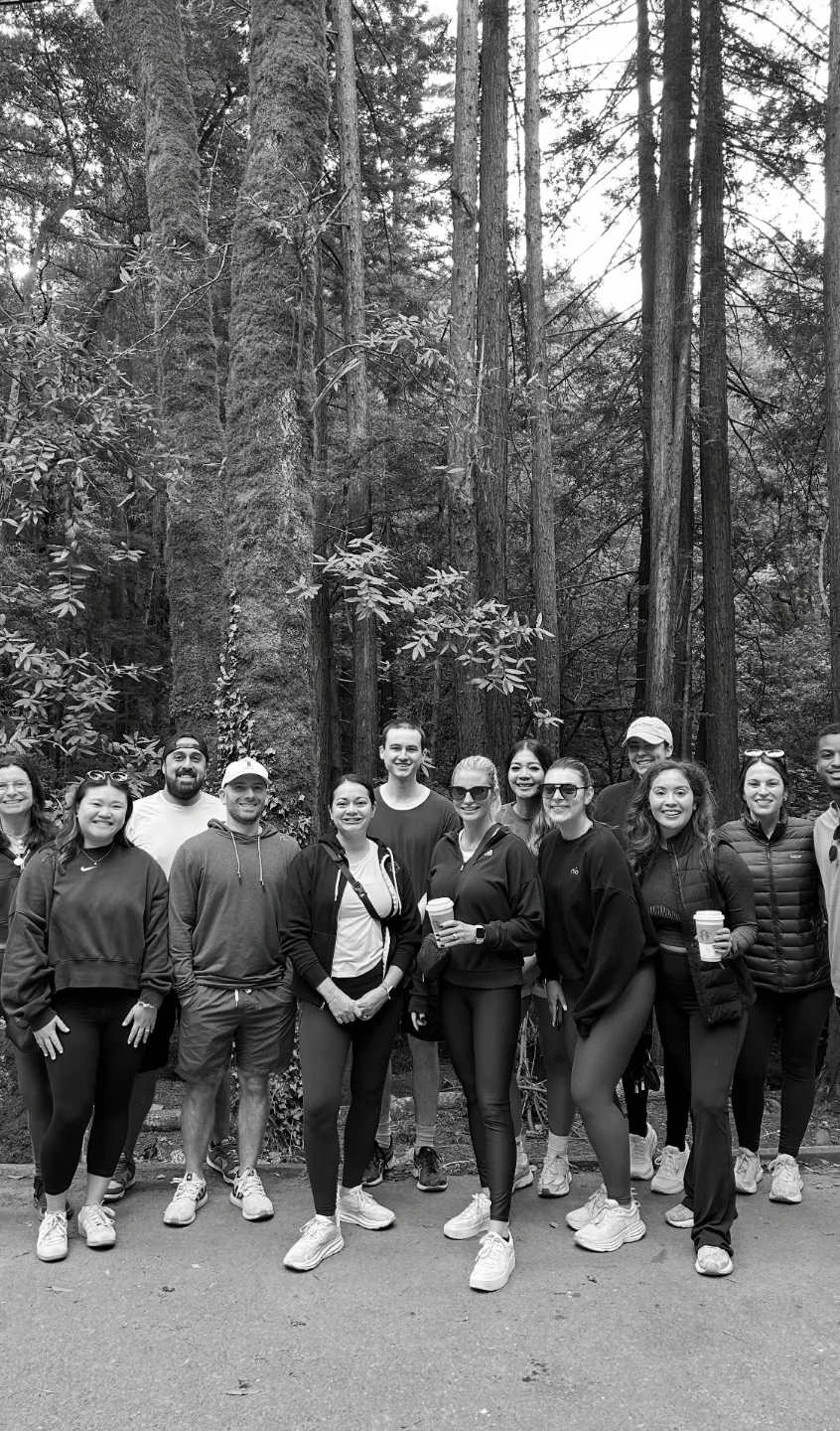Connery Team dressed in casual activewear posing on a forest trail with tall trees in the background.