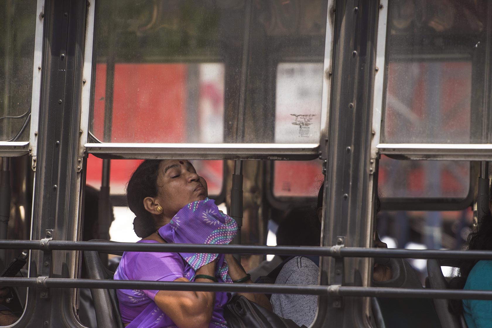 A lady on a bus next to a window trying to keep cool in a heatwave