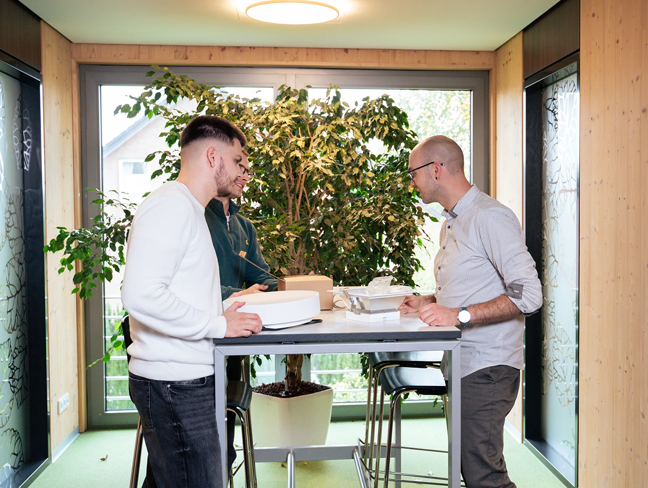 Mitarbeitende von Schröder & Partner – Beratende Ingenieure VBI für Elektrotechnik besprechen Leuchten und Lichttechnik am Stehtisch im Büro.