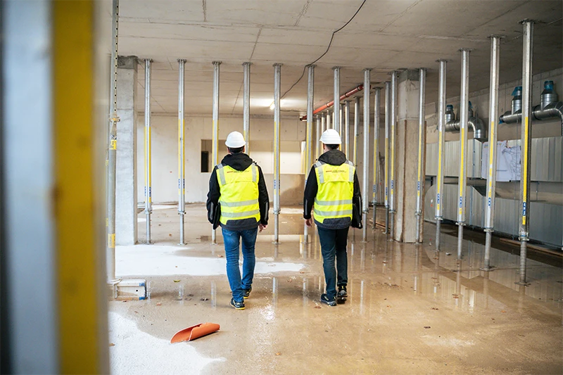 Zwei Mitarbeitende von Schröder & Partner – Beratende Ingenieure VBI für Elektrotechnik begehen eine Baustelle und kontrollieren die elektrotechnische Ausführung im Gebäude.