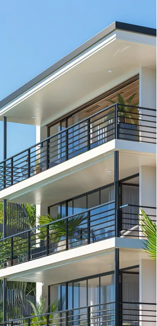 Beach house on stilts overlooking ocean waves during sunset with sandy dunes and vegetation in foreground.