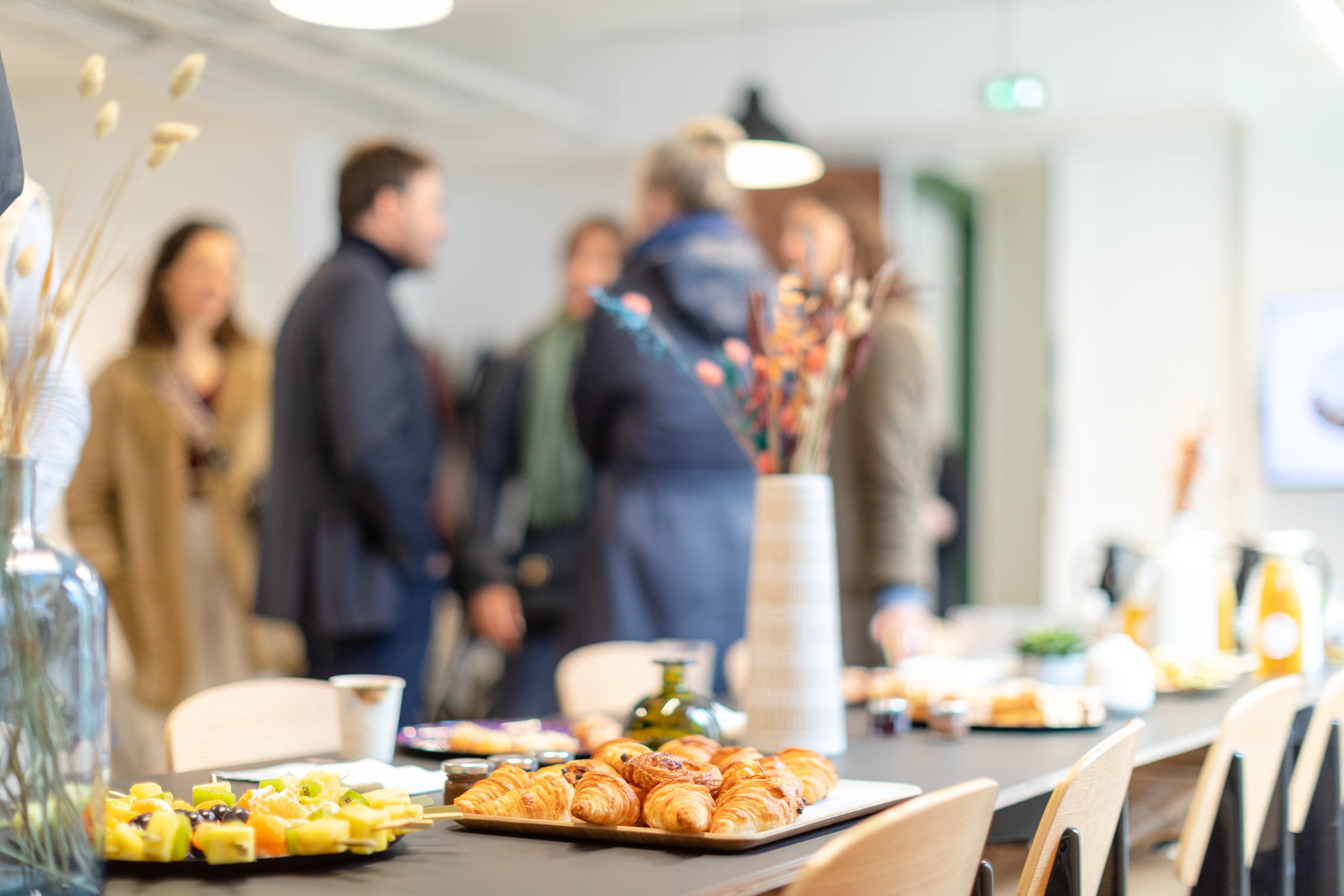 Des personnes discutant dans un open space avec des viennoiseries sur la table