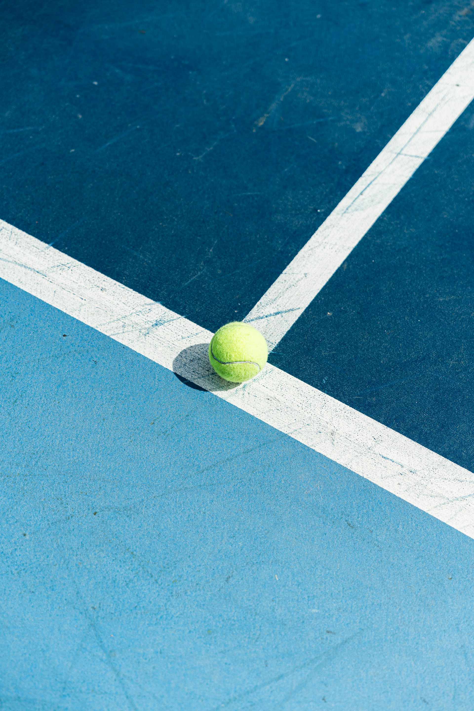 padel court blue coloured with a tennis ball on the ground off-court