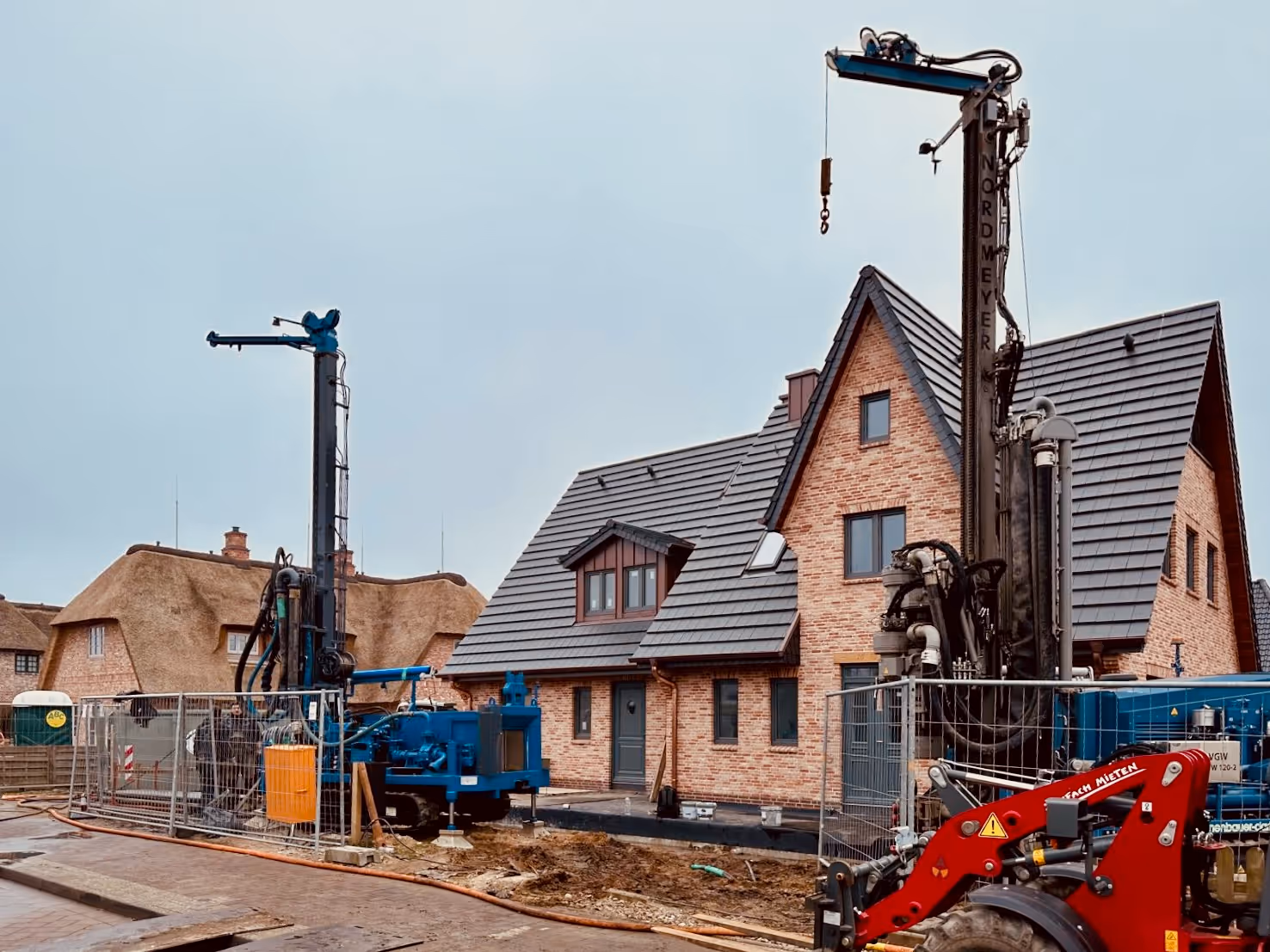 Arbejdere driver en blå boremaskine udenfor mellem træer ved solnedgang.
