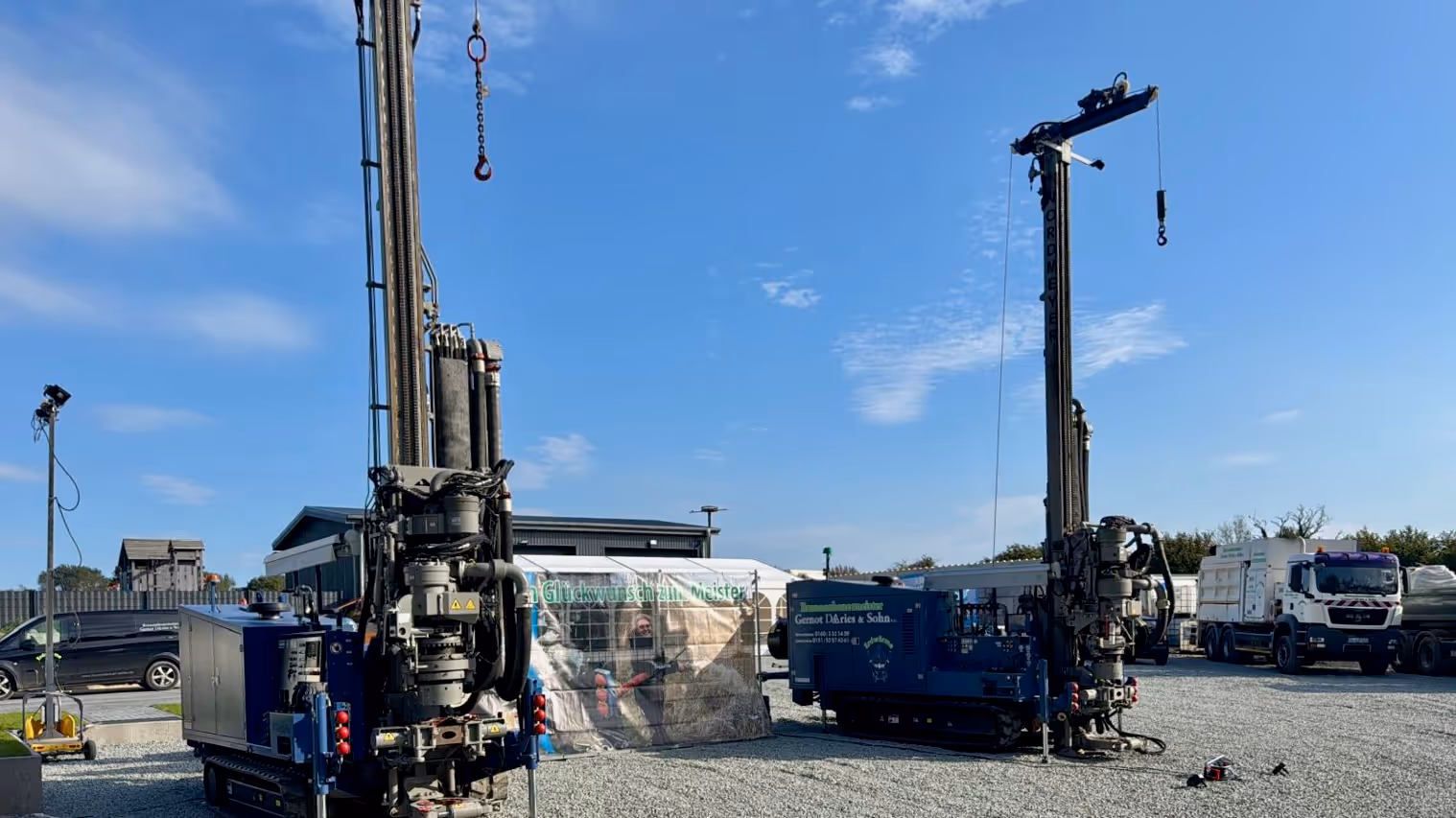 Bohrgerät auf einer Baustelle im Freien, umgeben von blattlosen Bäumen und blauen Rohren im Vordergrund.