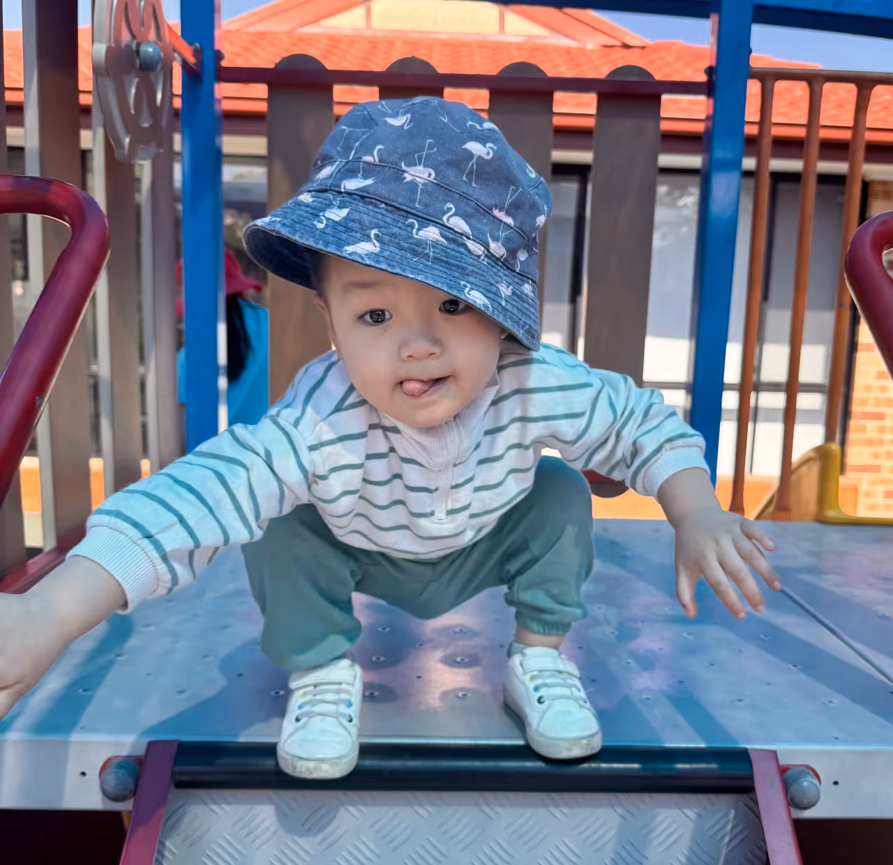 Smiling boy sitting at a classroom table with pencils and schoolwork in front of him.