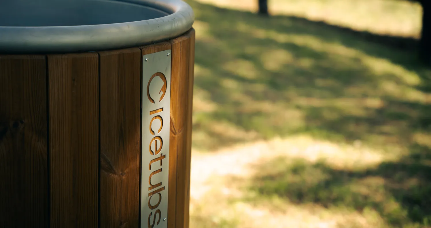 Close-up of a wooden outdoor hot tub with a metal logo plate reading 'Icetubs' on its side.