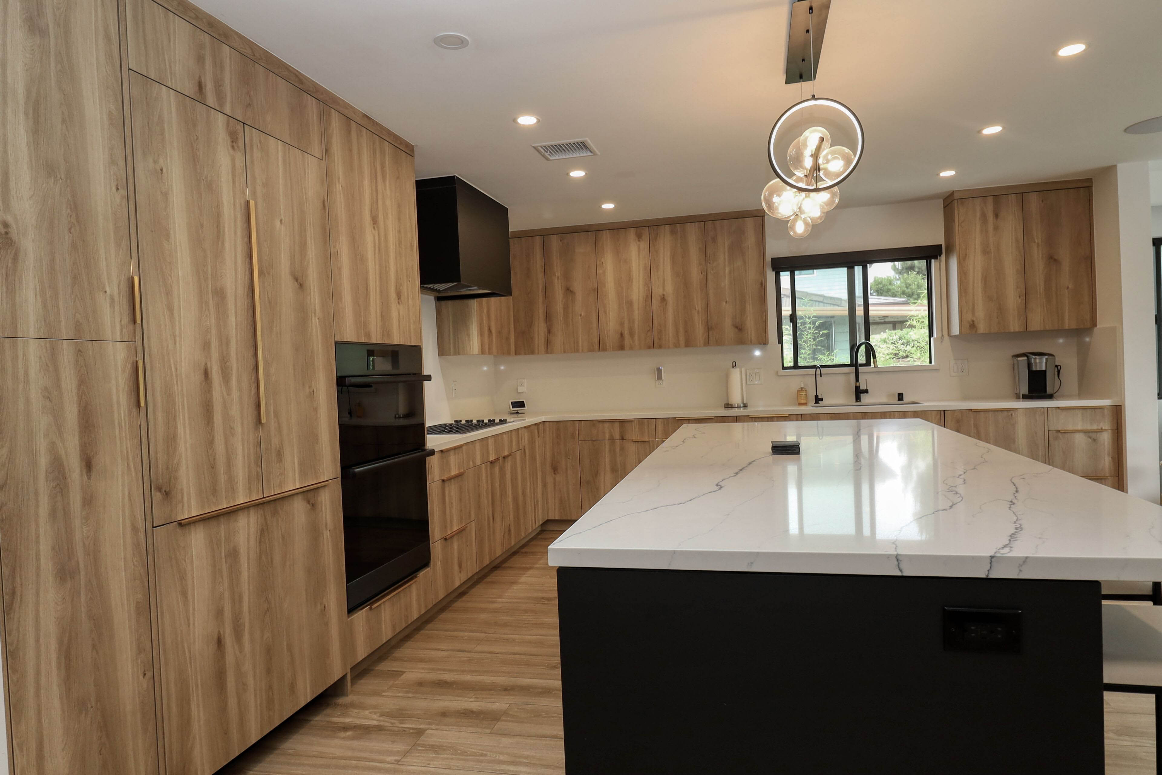 Modern kitchen with light wood cabinets, white quartz island countertop, black island base, and pendant lighting