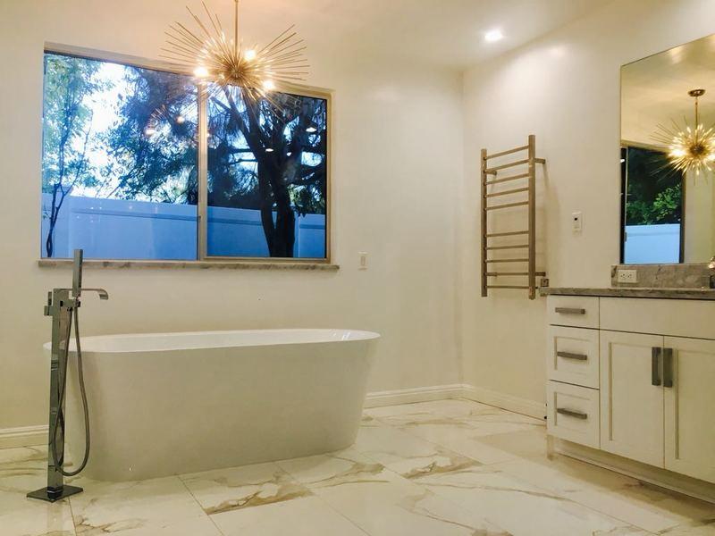 Custom bathroom remodel Los Angeles featuring freestanding soaking tub, heated towel rack and marble flooring