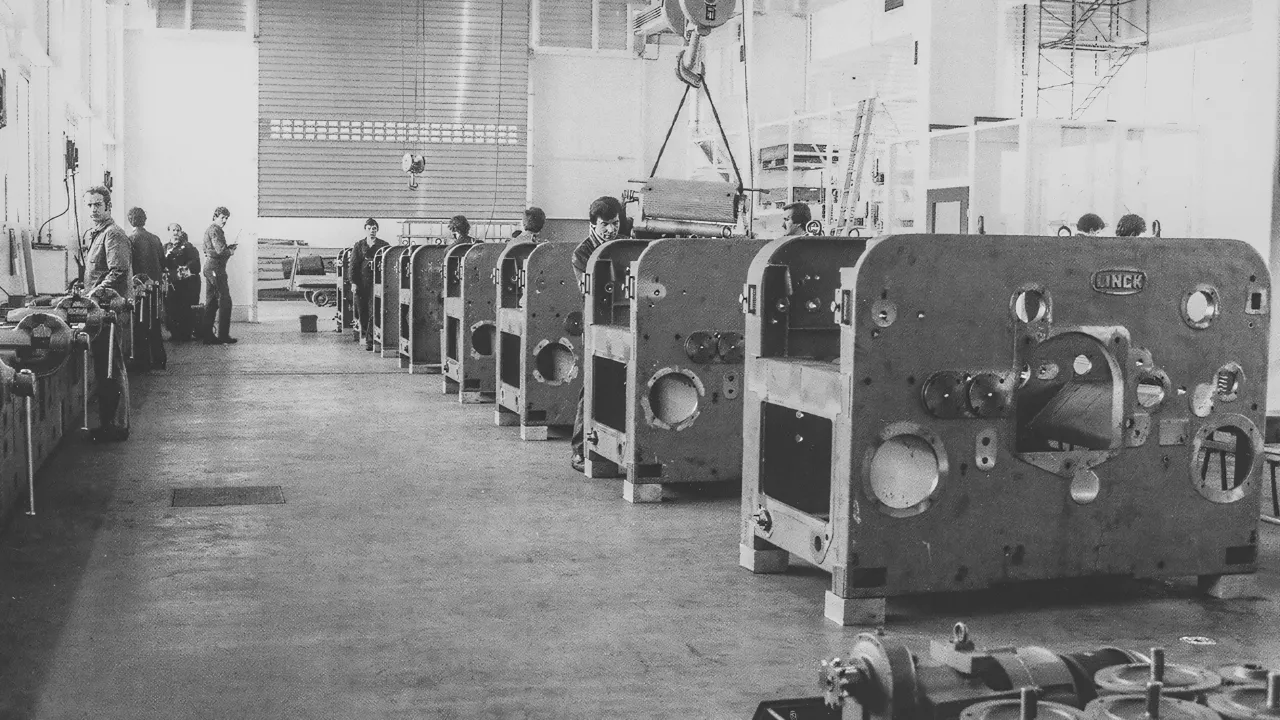 Historische Werksmontage bei LINCK aus dem frühen 18. Jahrhundert mit mehreren hintereinander stehenden Maschinen, an denen mehrere Mitarbeiter arbeiten.