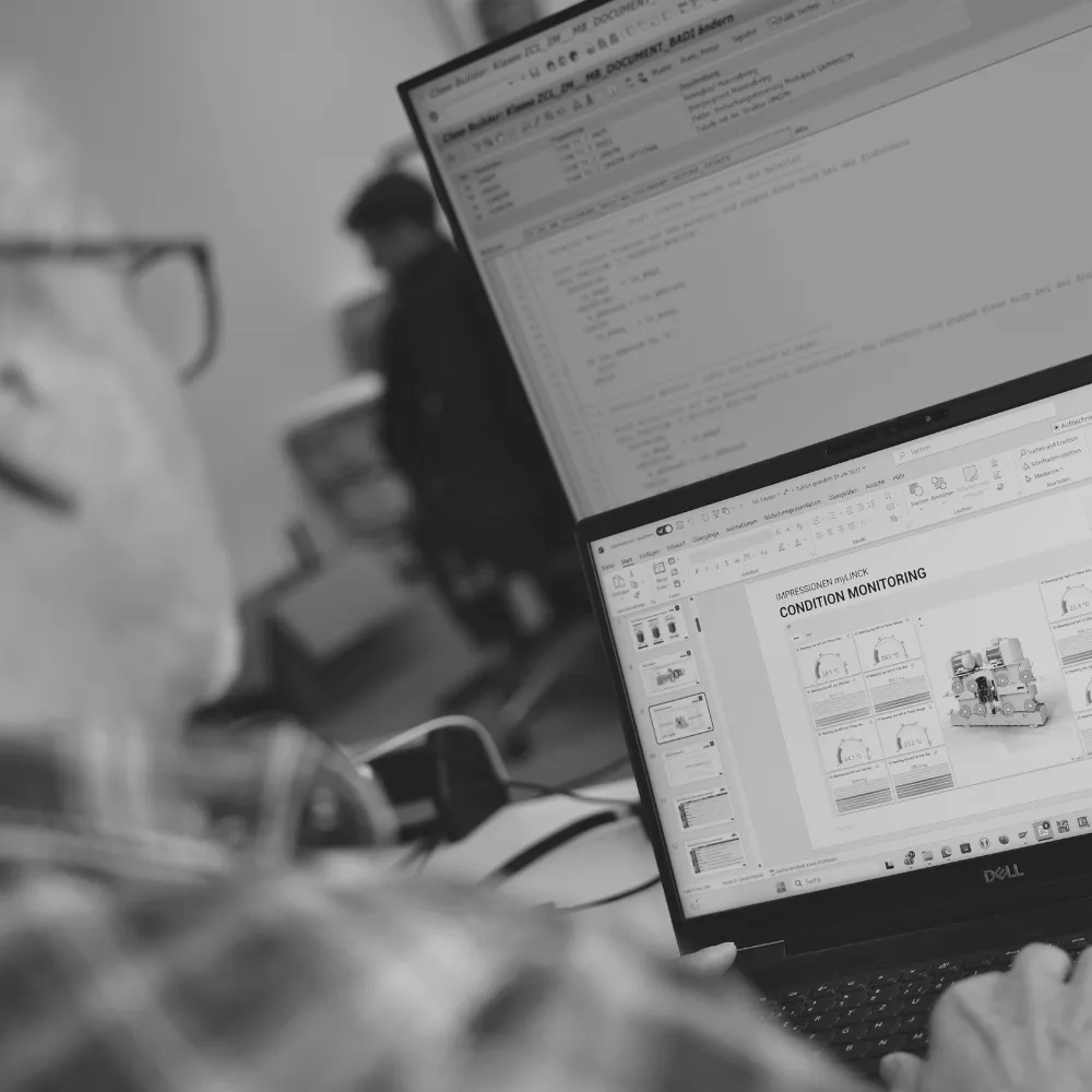 myLINCK Dashboard auf einem Laptop über der Schulter eines Mitarbeiters, geöffnet im Condition Monitoring mit 3D-Ansicht einer Maschine und grünen Zustandswerten