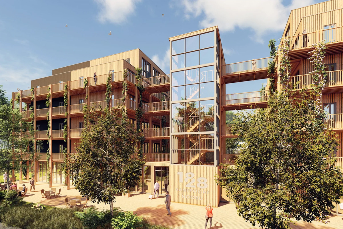 Buitenzijde van een modern houten appartementencomplex met balkons, een glazen trappenhuis, verbindende loopbruggen en bomen op de voorgrond.